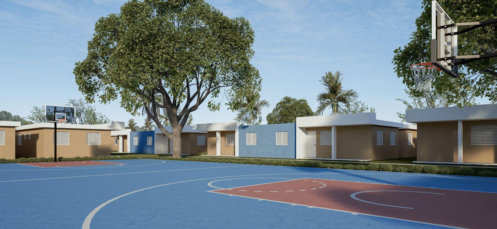 Outdoor basketball court with modern low-rise buildings and large trees in the background under a clear sky.